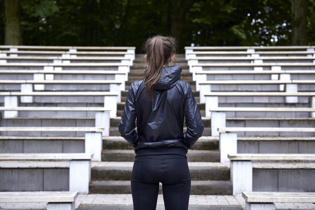 Rear view of young woman training, preparing to run up stadium stairway